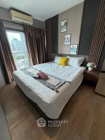 Cozy bedroom with city view, featuring a large bed, stylish decor, and natural light from a window.