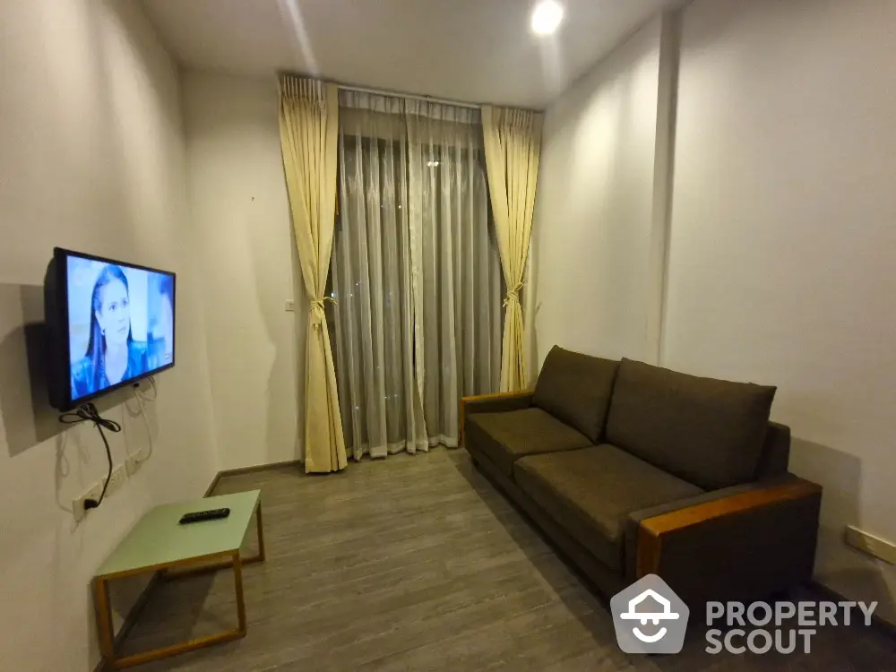 Modern living room with cozy sofa and wall-mounted TV, featuring elegant curtains and sleek flooring.