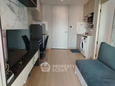 Modern studio apartment with sleek design, featuring a TV, washing machine, and stylish furnishings.