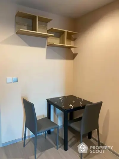 Modern dining nook with sleek table and chairs, featuring stylish wall-mounted shelves.