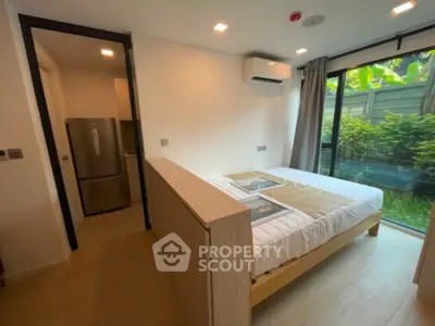 Modern bedroom with garden view and air conditioning, featuring a cozy bed and sleek refrigerator.
