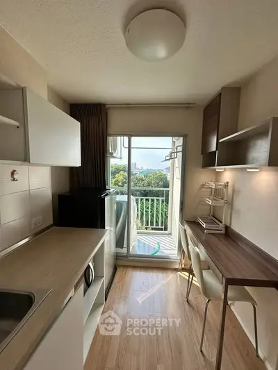 Charming compact kitchen with balcony view, perfect for urban living.