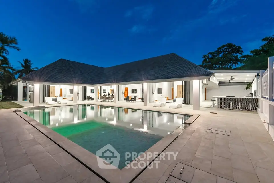 Luxurious modern villa with expansive pool and elegant outdoor lighting at dusk.