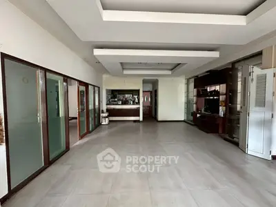 Spacious open-plan living area with modern ceiling design and large windows.