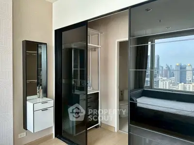 Modern bedroom with city view, featuring sleek glass wardrobe and stylish decor.