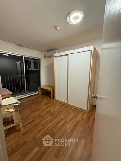 Spacious bedroom with wooden flooring and sliding wardrobe doors, ideal for modern living.