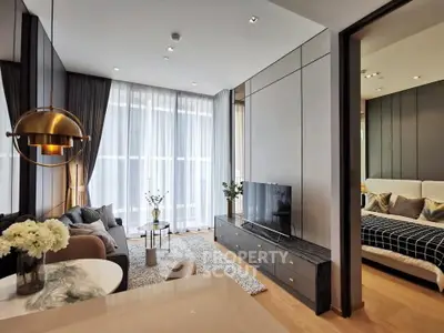 Modern living room with elegant decor and open layout leading to a cozy bedroom.