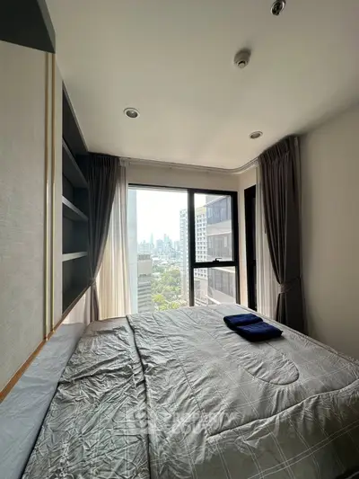 Modern bedroom with city view, featuring large windows and stylish decor in a high-rise apartment.