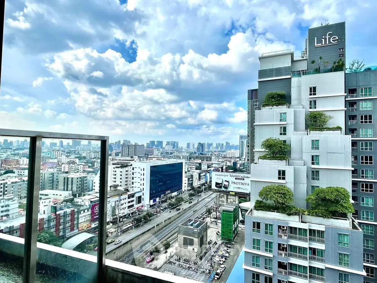 Stunning cityscape view from a modern high-rise balcony with lush greenery and urban skyline.
