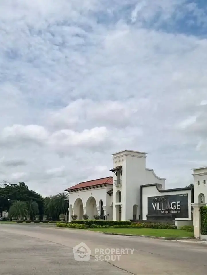 Elegant entrance of Golden Village with lush greenery and clear skies.
