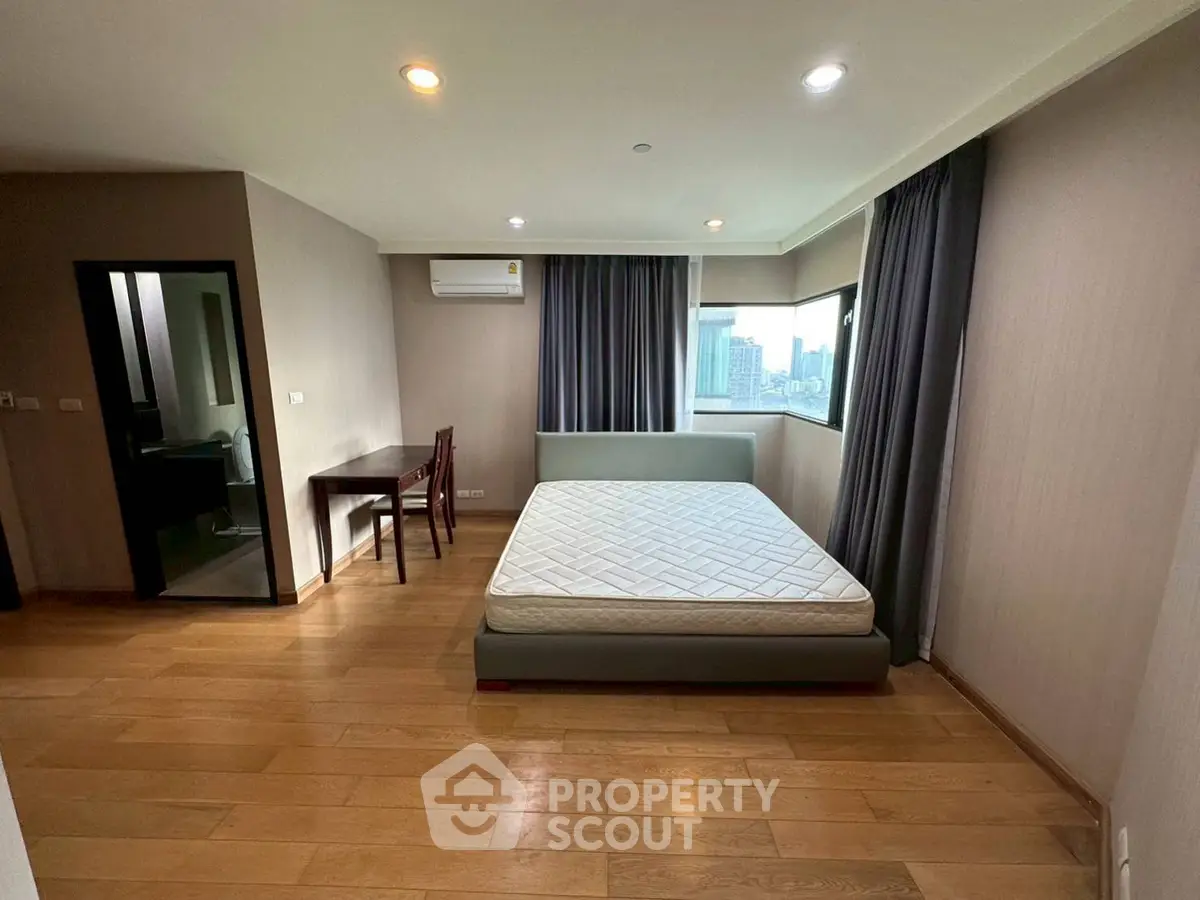 Spacious bedroom with city view, featuring a comfortable bed and study area, perfect for urban living.