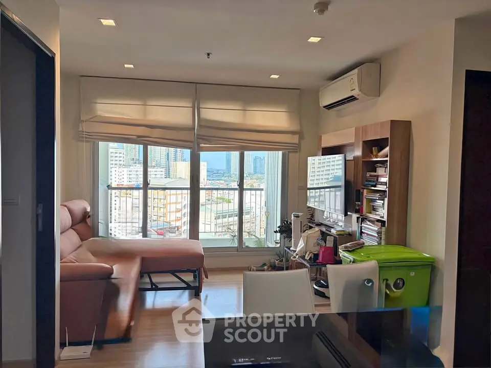Modern living room with city view, featuring a cozy sofa, air conditioning, and large windows for natural light.