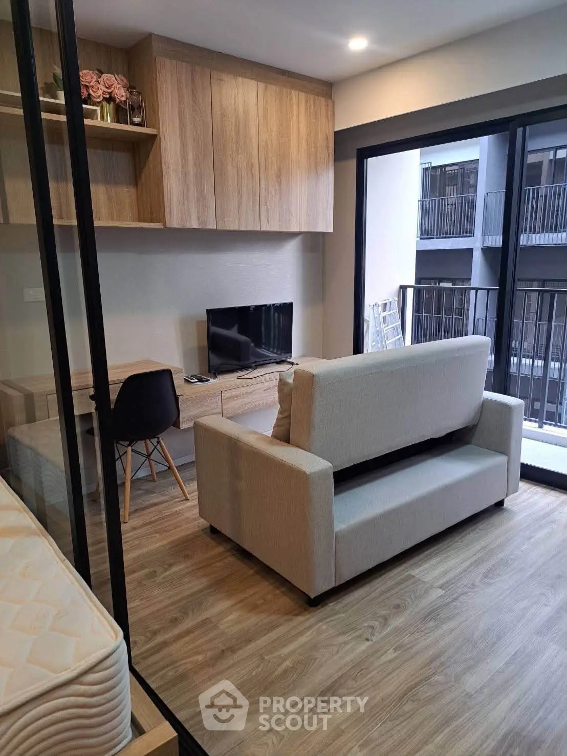 Modern living room with balcony view, featuring sleek furniture and wooden flooring.