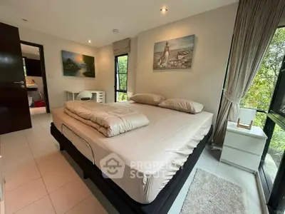 Spacious bedroom with large windows and elegant decor in modern home.