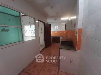 Spacious kitchen with tiled flooring and vibrant orange backsplash