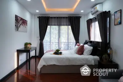 Luxurious bedroom with elegant decor and balcony view, featuring modern lighting and stylish furnishings.