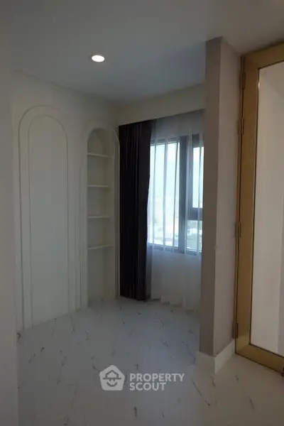 Bright and modern room with large window and built-in shelving, perfect for a cozy living space.