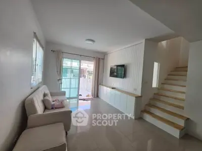 Modern living room with sleek design and natural light, featuring a cozy sofa and wall-mounted TV.