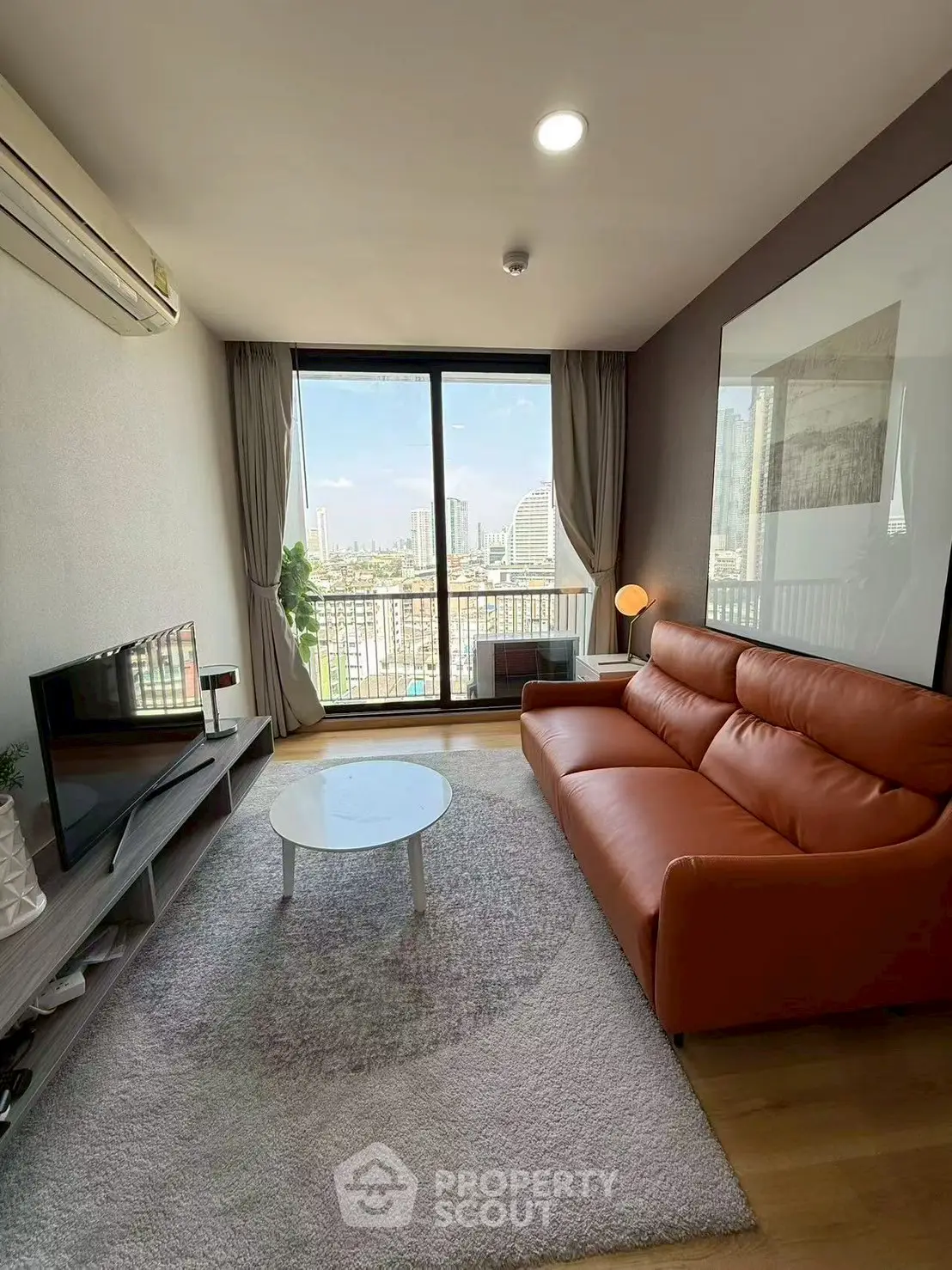 Modern living room with city view, featuring a stylish orange sofa and sleek decor.
