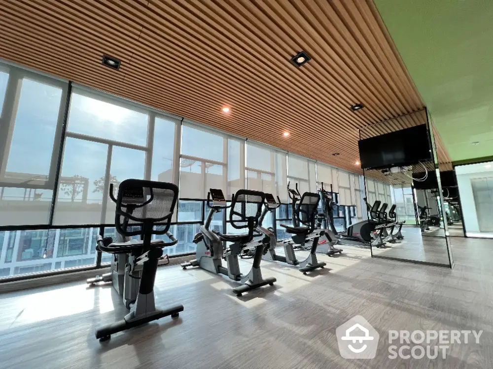 Modern gym with exercise bikes and large windows in luxury apartment building