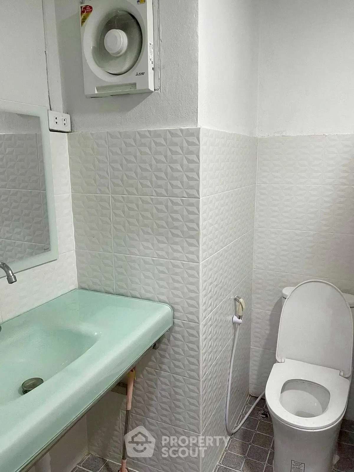 Modern bathroom with sleek sink and toilet, featuring textured wall tiles and ventilation fan.