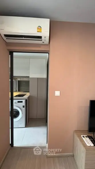 Modern apartment interior with air conditioning and laundry area, featuring a washing machine and sleek design.
