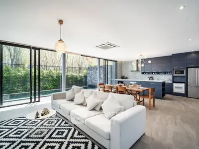 Spacious modern living room with open kitchen and large windows overlooking greenery.
