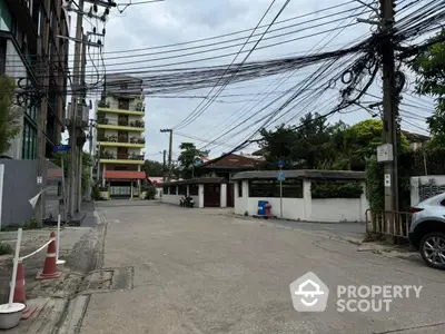 Quiet residential street with apartment buildings and lush greenery, perfect for urban living with a suburban feel.