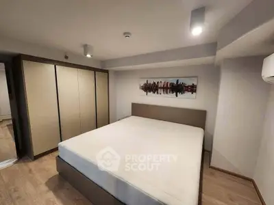 Spacious modern bedroom with large bed and stylish wardrobe in a contemporary apartment.