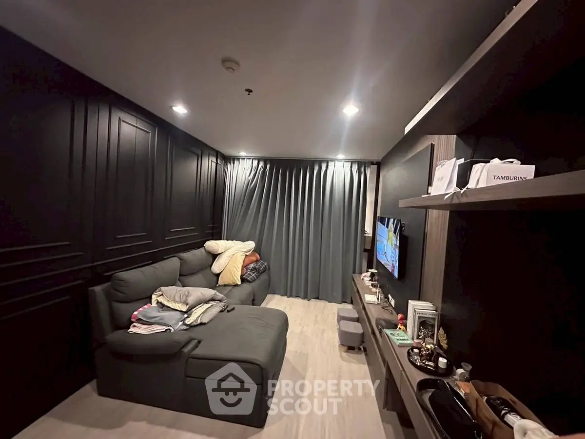 Modern living room with sleek black walls, cozy gray sofa, and stylish shelving unit.