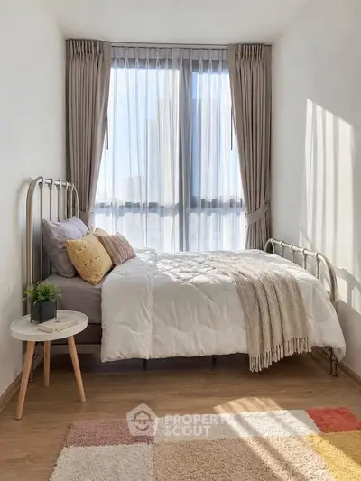 Cozy bedroom with modern decor and large window offering natural light.