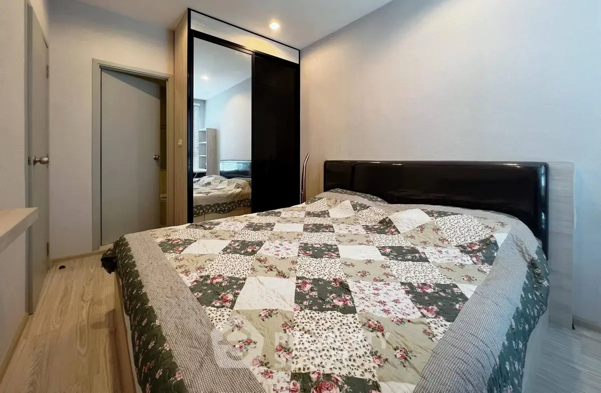 Cozy bedroom with stylish quilted bedspread and mirrored wardrobe in modern apartment.