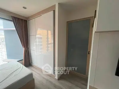 Modern bedroom with large window and built-in wardrobe in a high-rise apartment.