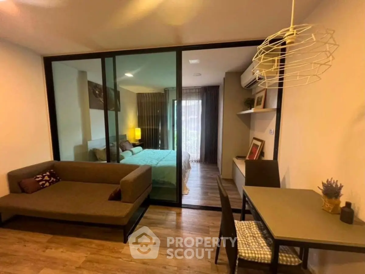 Modern studio apartment with glass partition, cozy living area, and stylish decor.