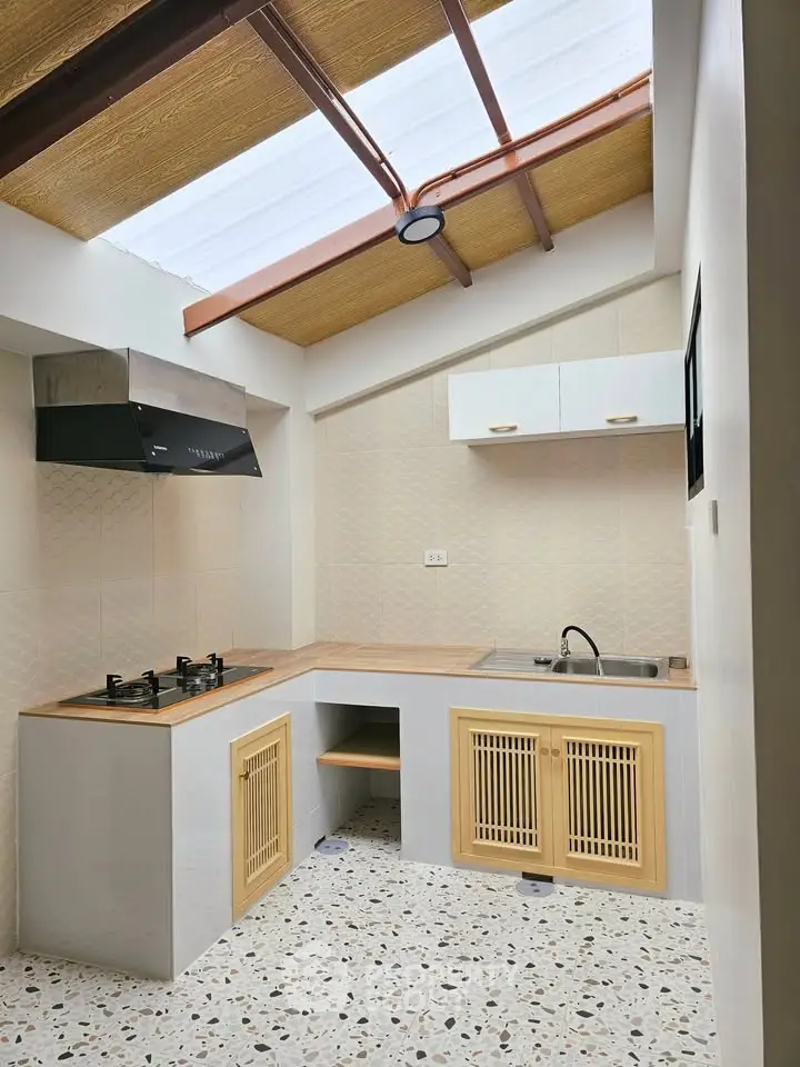 Charming kitchen with modern gas stove and skylight, featuring terrazzo flooring and wooden cabinetry.
