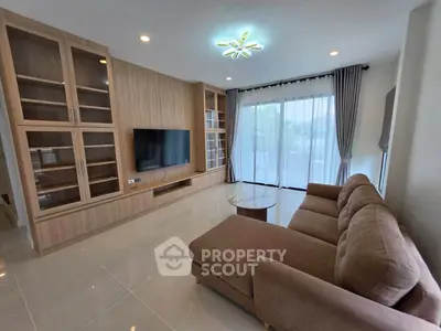 Spacious living room with modern sofa and built-in TV cabinet, featuring large windows for natural light.
