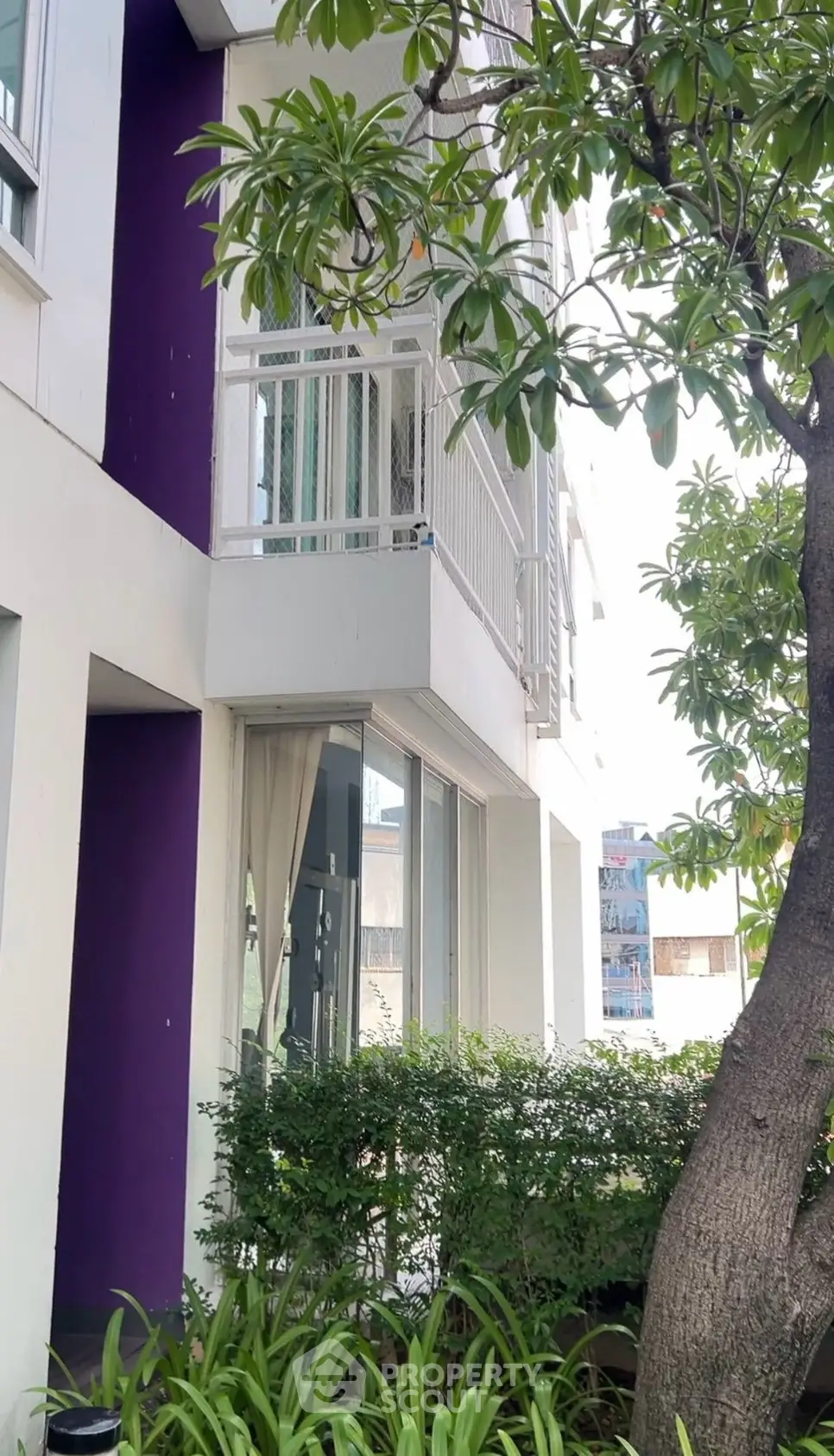 Charming modern apartment exterior with lush greenery and balcony, perfect for urban living.