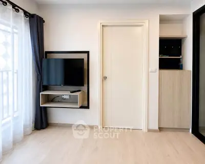 Modern living room with wall-mounted TV and light wood flooring, featuring a sleek storage unit.