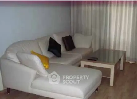 Cozy living room with modern white sectional sofa and glass coffee table, perfect for relaxation.