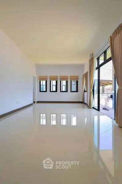 Spacious empty living room with large windows and glossy tiled floor.