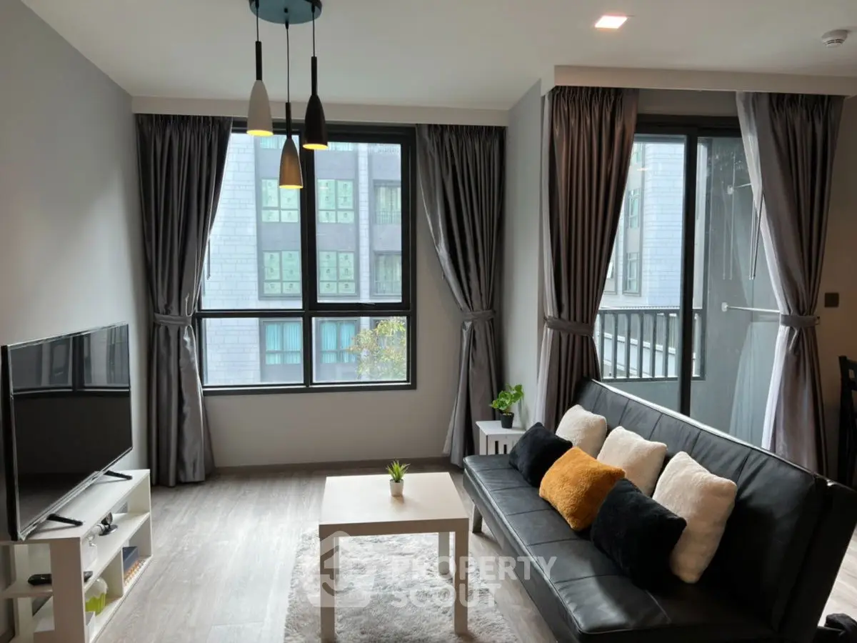 Modern living room with sleek decor, large windows, and stylish lighting in urban apartment.