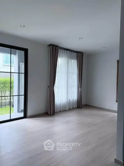 Spacious empty living room with large window and garden view, perfect for customization.
