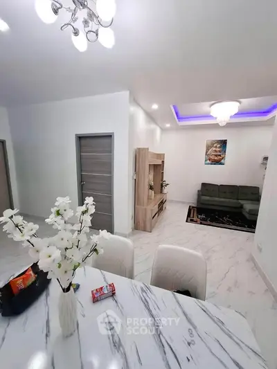 Modern living room with elegant decor and open layout, featuring a stylish chandelier and marble flooring.