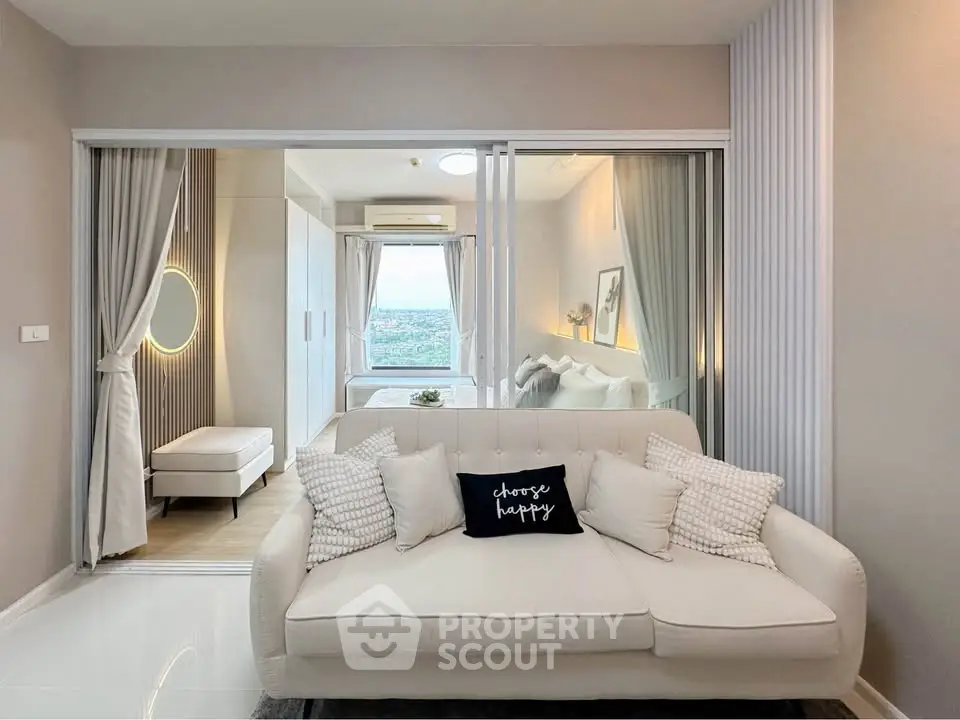 Modern living room with cozy sofa and view into stylish bedroom through glass doors.