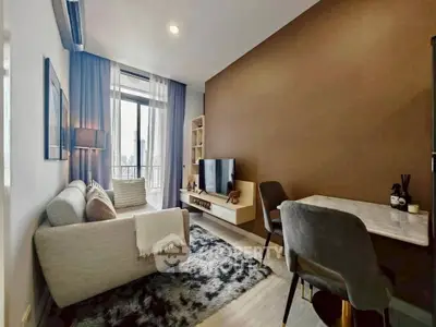 Modern living room with cozy seating, stylish decor, and natural light from large window.