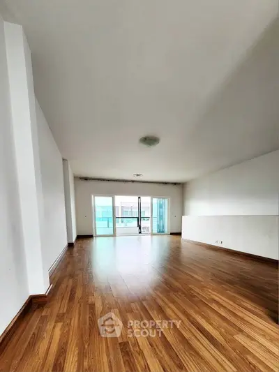 Spacious empty living room with wooden flooring and large windows