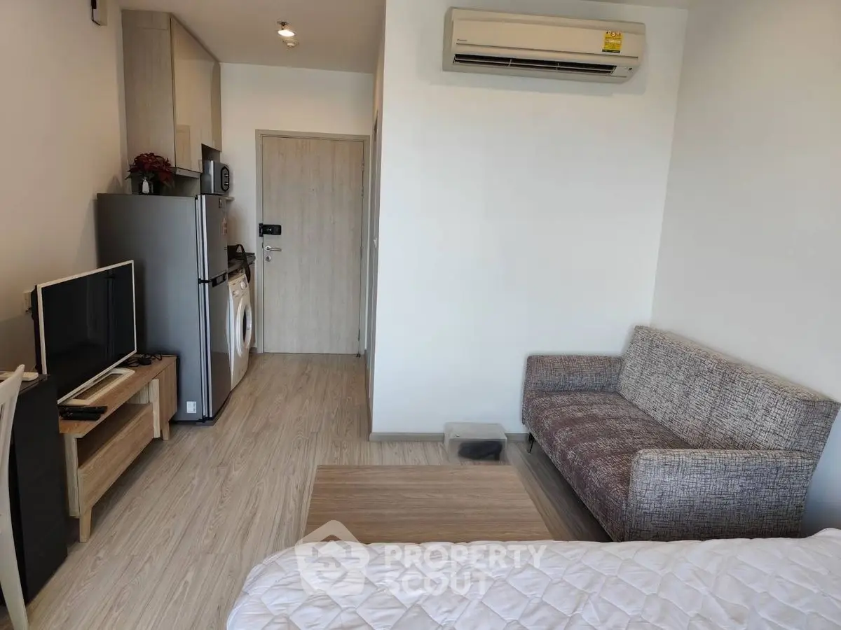 Modern studio apartment with cozy living area and compact kitchen appliances.