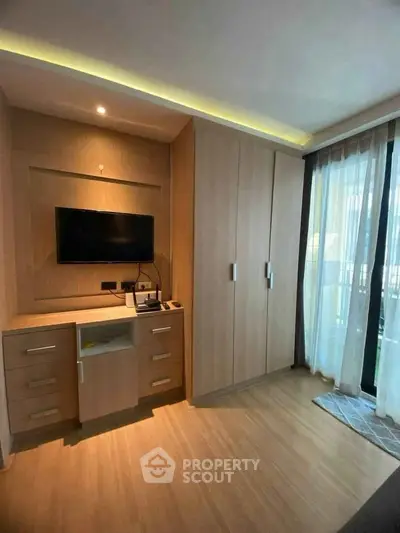 Modern bedroom with built-in wardrobe and TV, featuring floor-to-ceiling windows.