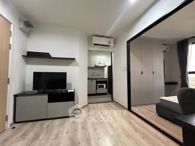 Modern apartment interior with open living room and kitchen, featuring sleek furniture and wood flooring.