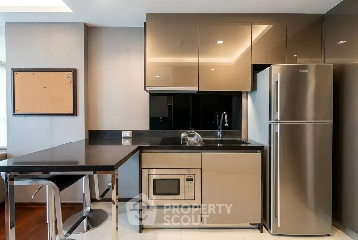 Modern kitchen with sleek cabinetry, stainless steel appliances, and breakfast bar in a stylish apartment.